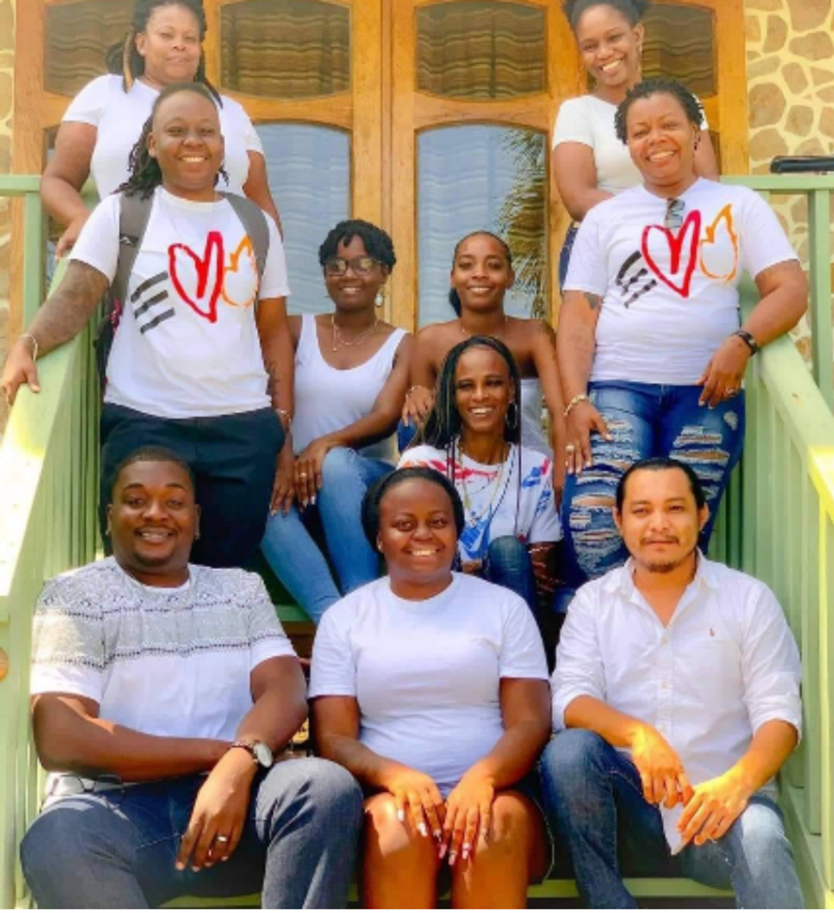 A group of people in white tshirts gather on the steps outside